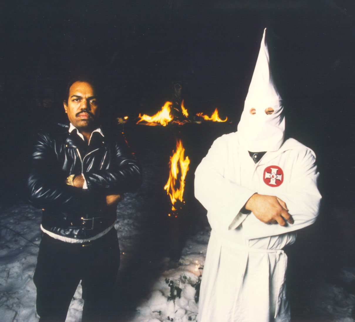 Dr. Daryl Davis is a civil rights activist who has built bridges with white supremacists and KKK members, inspiring them to change. He is pictured here with a KKK member with a burning cross in the background.